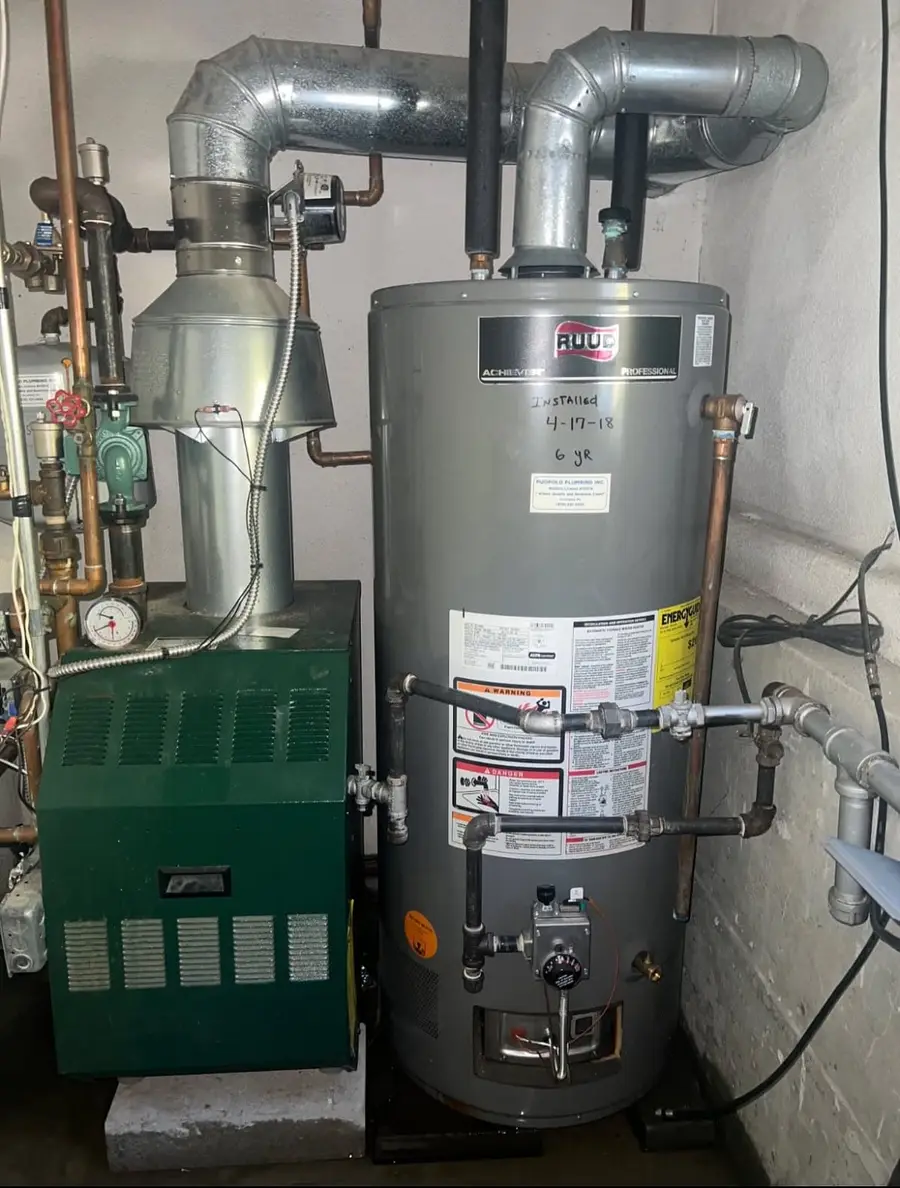 New water heater next to a green cast-iron boiler