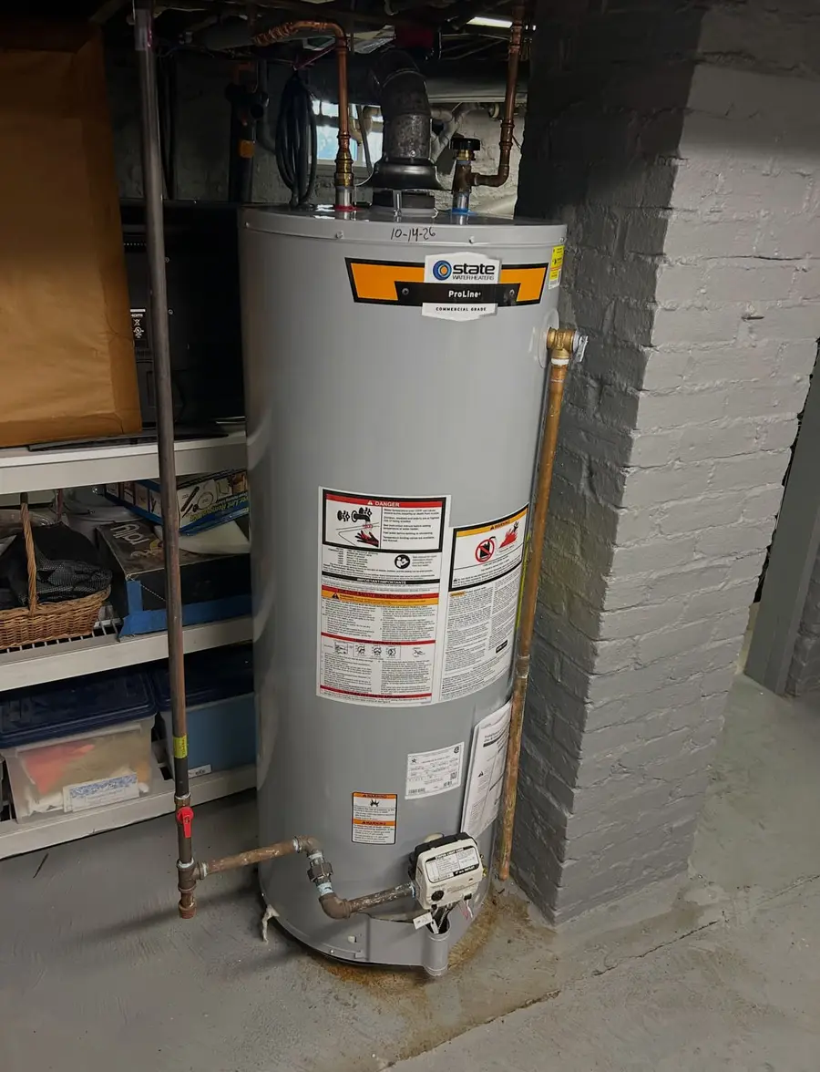 New 50-gallon gas water heater against a brick wall