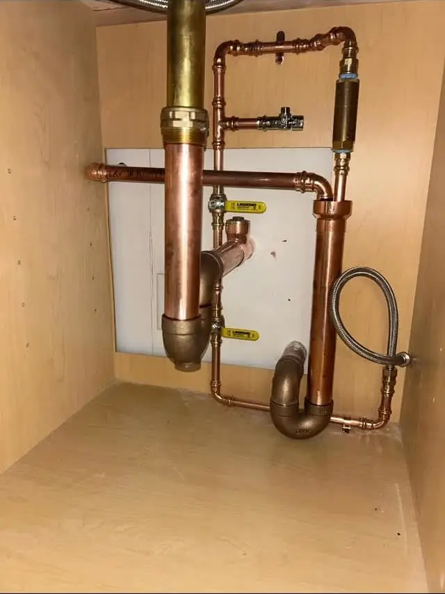 Copper hot and cold piping and trap under a sink in a Lexington office