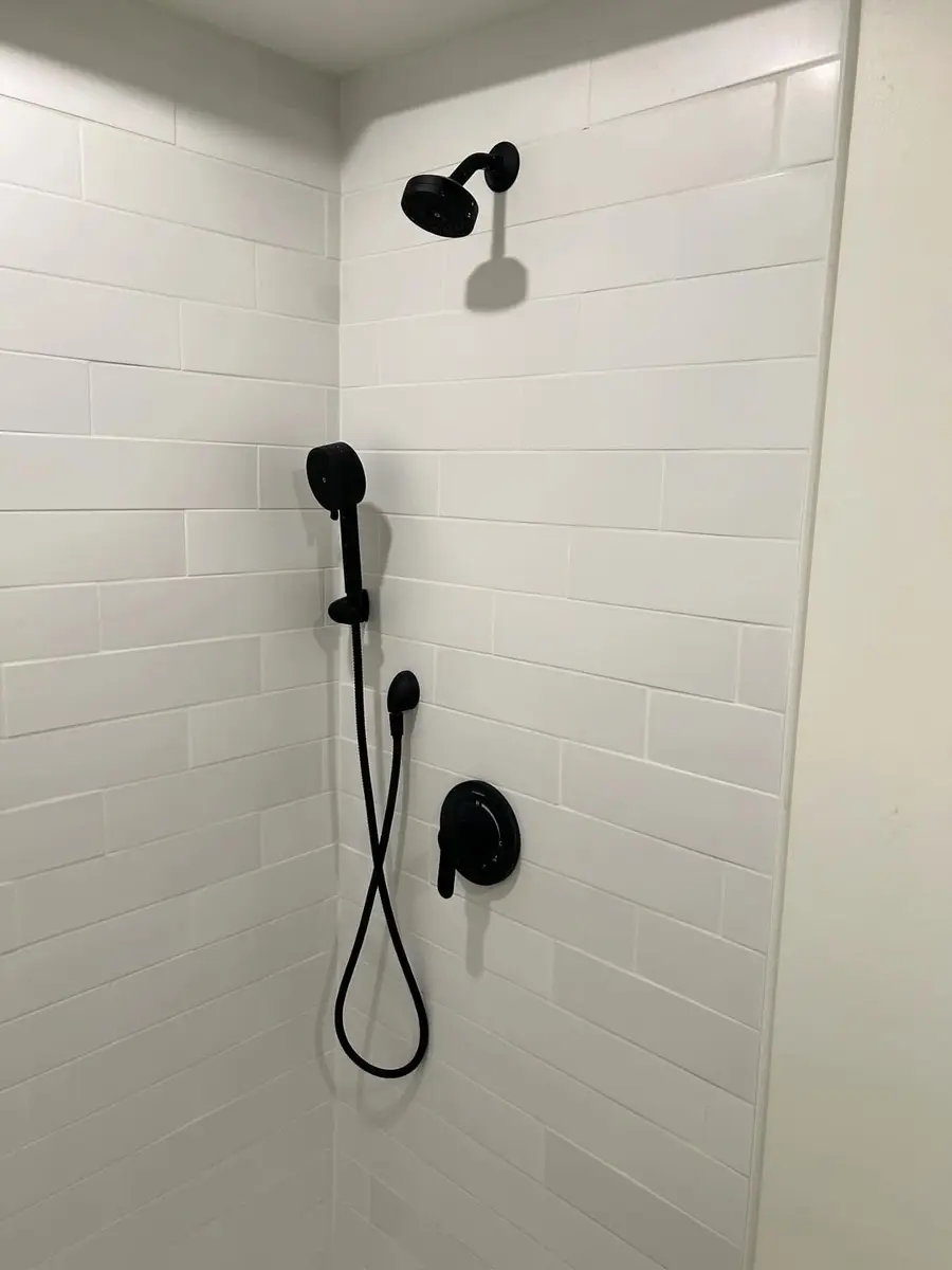 Tiled shower with black trim and a hand shower